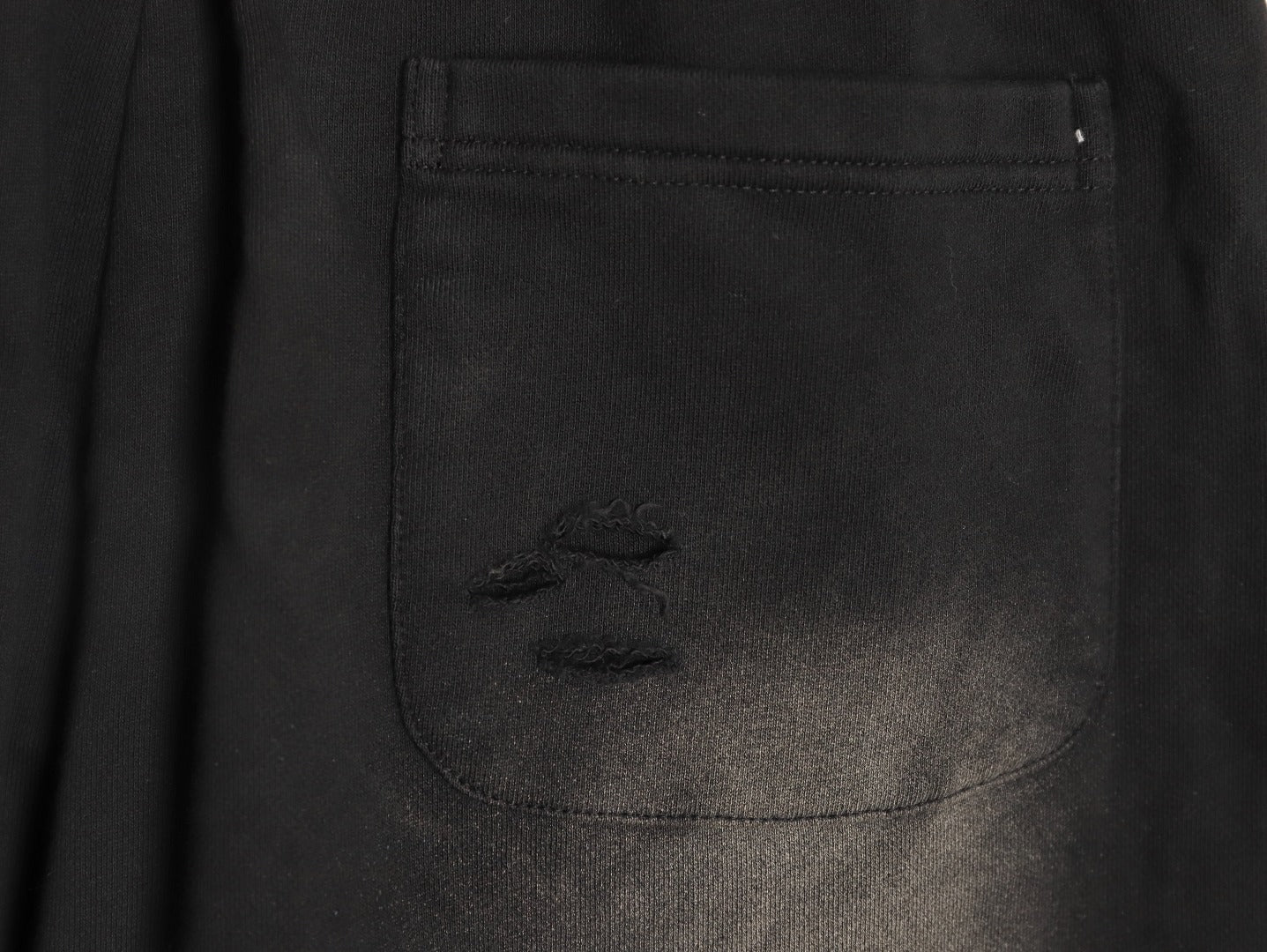 Balenciaga distressed shorts with a blurred Coca-Cola logo.